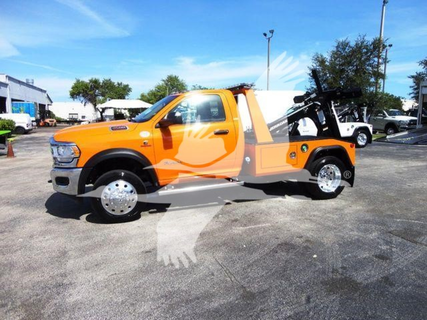Ram 4500 SLT tow truck with bright orange body and black winch equipment in bed, side view showing truck cab and wheel rims.