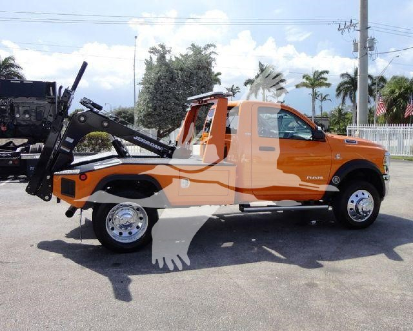 2024 Ram 4500 SLT tow truck side view showing bright orange body, tow winch mechanism, dual rear wheels, chrome rims, and Silverado-like front cab with Ram badge.