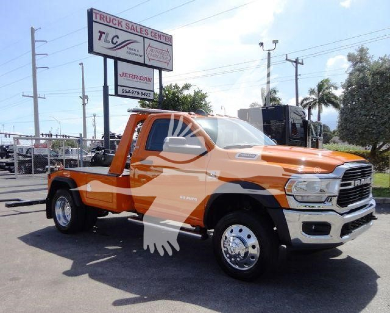 Ram 4500 SLT truck in orange with tow truck bed and chrome front grille, parked at dealership lot.