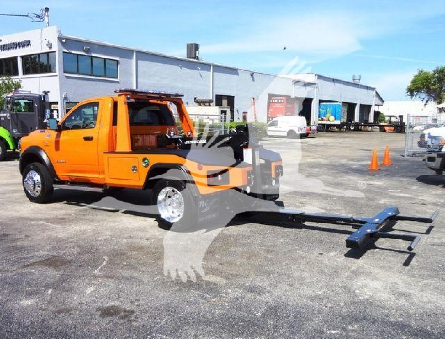 Ram 4500 SLT truck with an extended wheelbase and a mounted winch hitch, orange cab, black equipment, and a long tow bar in a dealership lot.