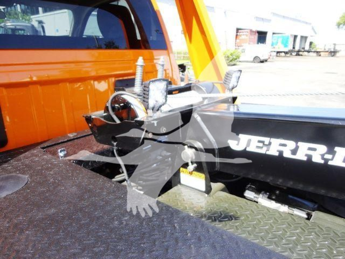 Ram 4500 SLT winch setup on bed, showing winch cable and hook assembly mounted on truck bed with orange body; JERR-DYNE/ROCK brand visible on winch components.