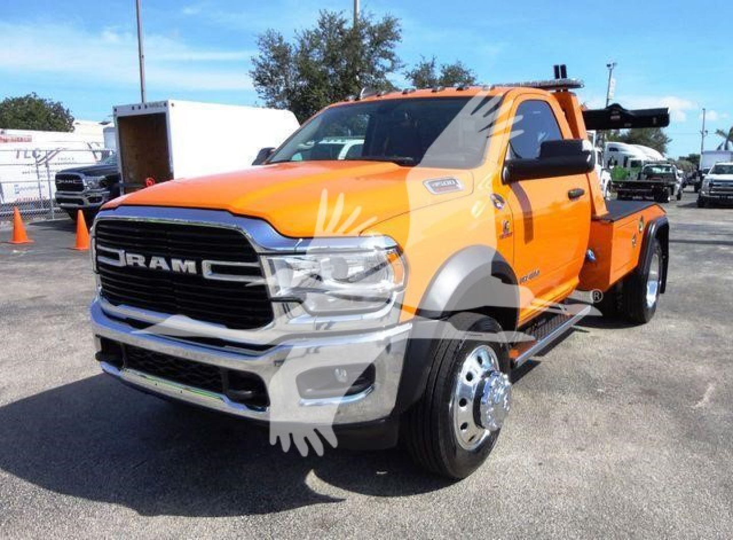 Ram 4500 tow truck front left view showing orange cab, chrome grille, large dual rear wheels, and winch equipment mount.