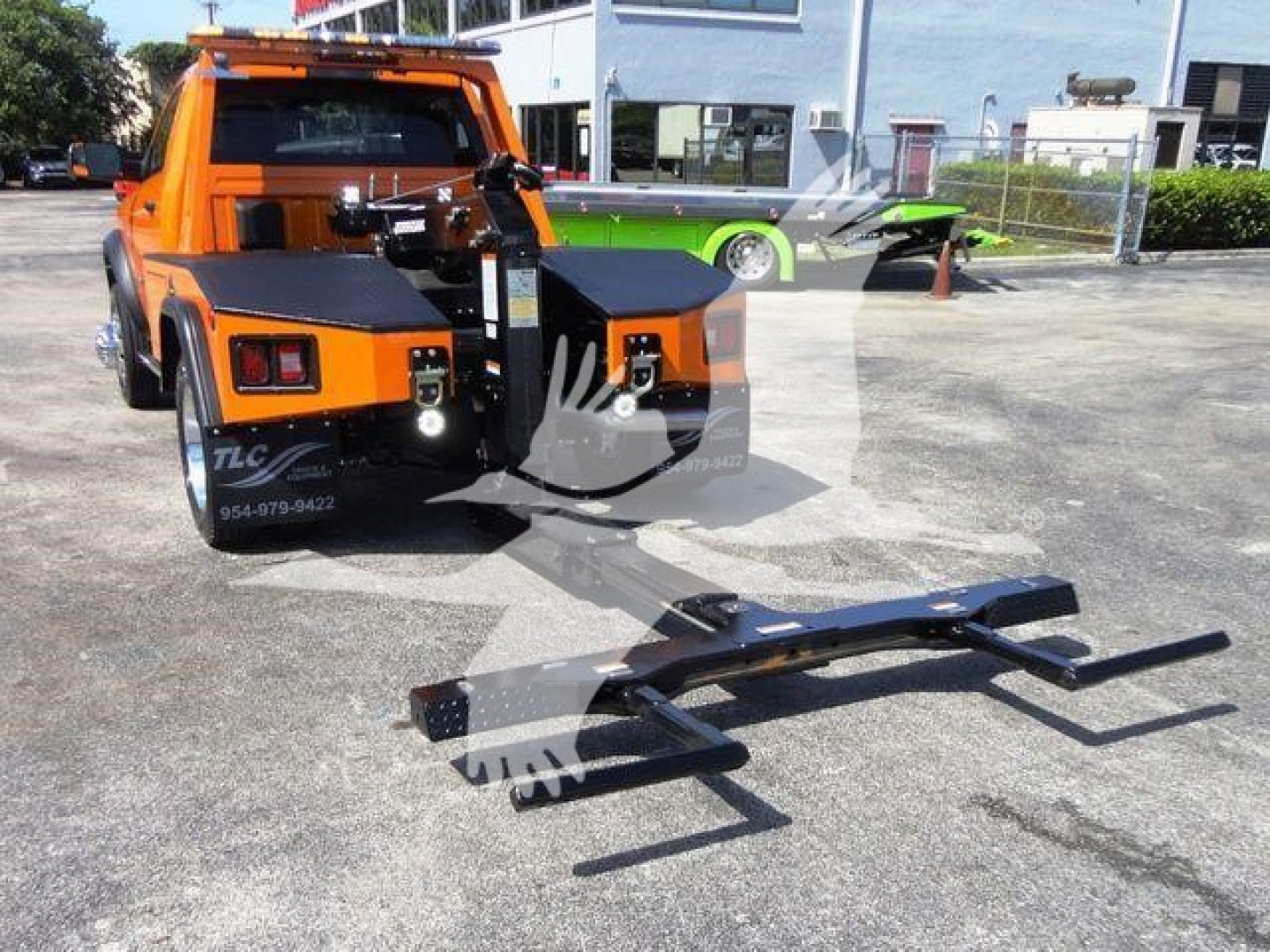 Front view of a bright orange Ram 4500 tow truck with a heavy-duty winch setup and a detachable puller bar resting on the ground.