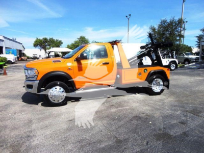 Ram 4500 SLT tow truck with bright orange body and black winch equipment in bed, side view showing truck cab and wheel rims.