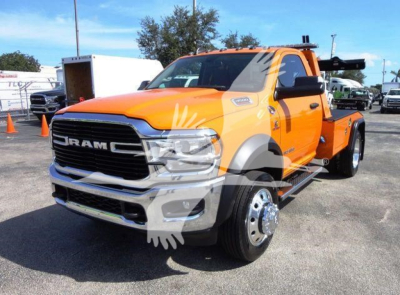 Ram 4500 tow truck front left view showing orange cab, chrome grille, large dual rear wheels, and winch equipment mount.