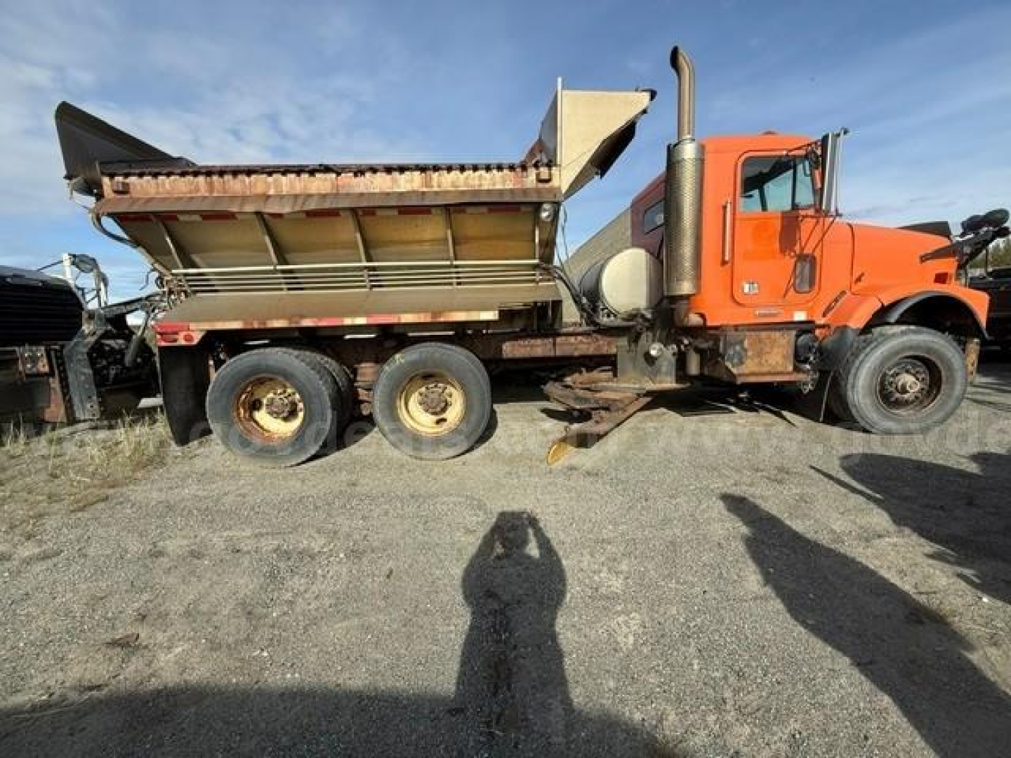 Truck side view of a 2002 Freightliner FLD120 dump truck with orange cab and dump bed, VIN 1FVHALCG52LJ57622.