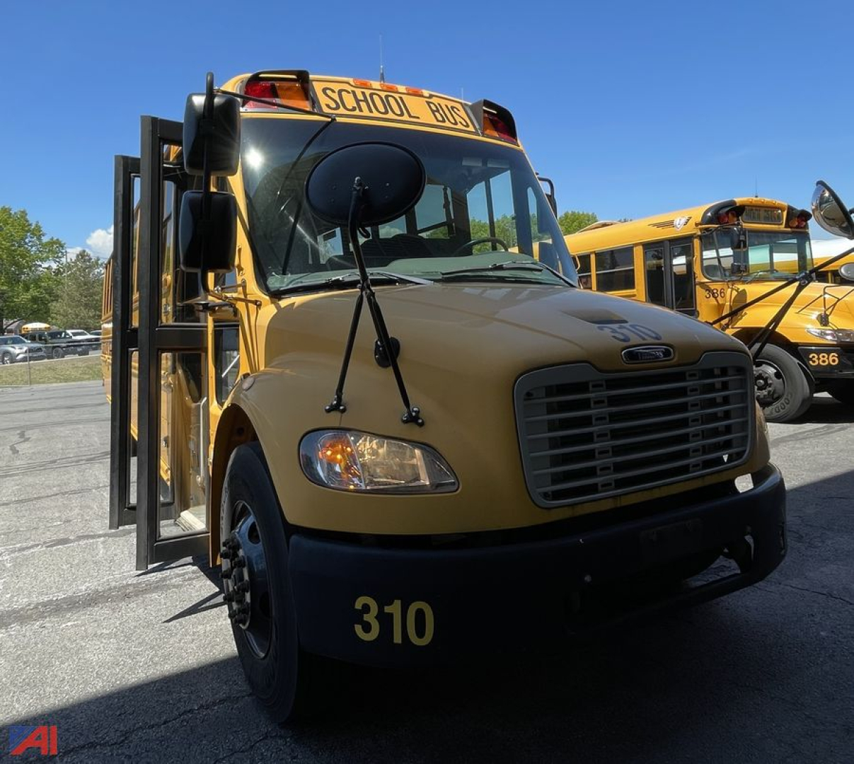 Bus front view showing yellow 2013 Freightliner C2 school bus with black grille and 310 number on bumper; 'SCHOOL BUS' sign on top.