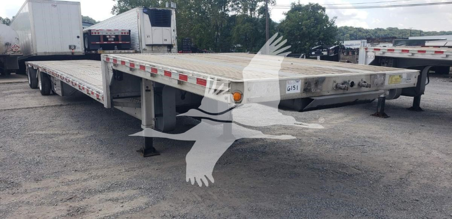 Dropdeck trailer showing flatbed with hydraulic drop mechanism and orange marker lights.