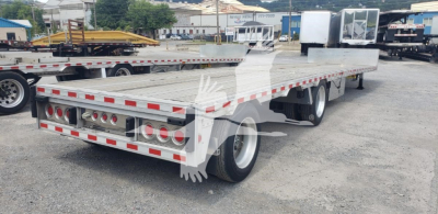 2018 Reitnouer Dropmiser trailer side/rear view showing flatbed with aluminum deck, tandem axles, rear lights, and reflective tape.