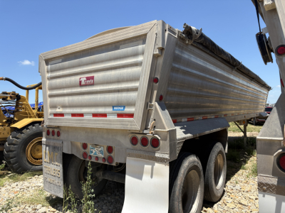 Travis dump trailer rear view showing aluminum side panels and dual rear axles with mud flaps.