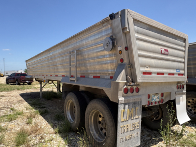 Travis Wave dump trailer showing rear and side with aluminum sides and dual rear axles.