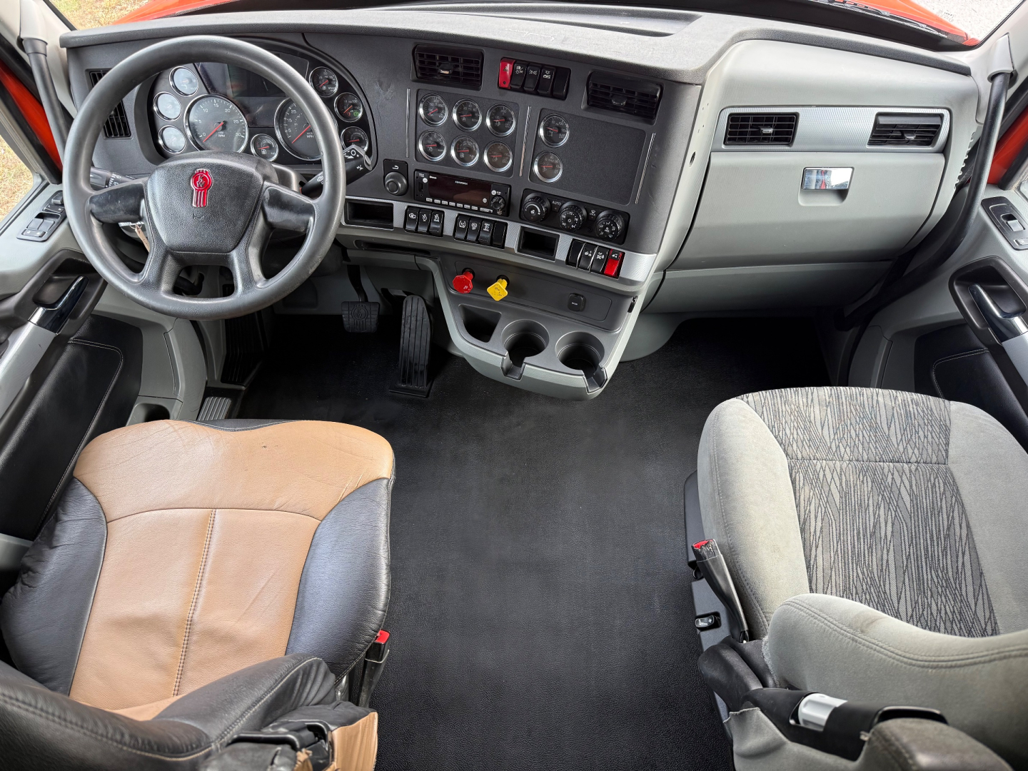 Kenworth T680 truck cab interior showing steering wheel and dashboard with gauges and controls.