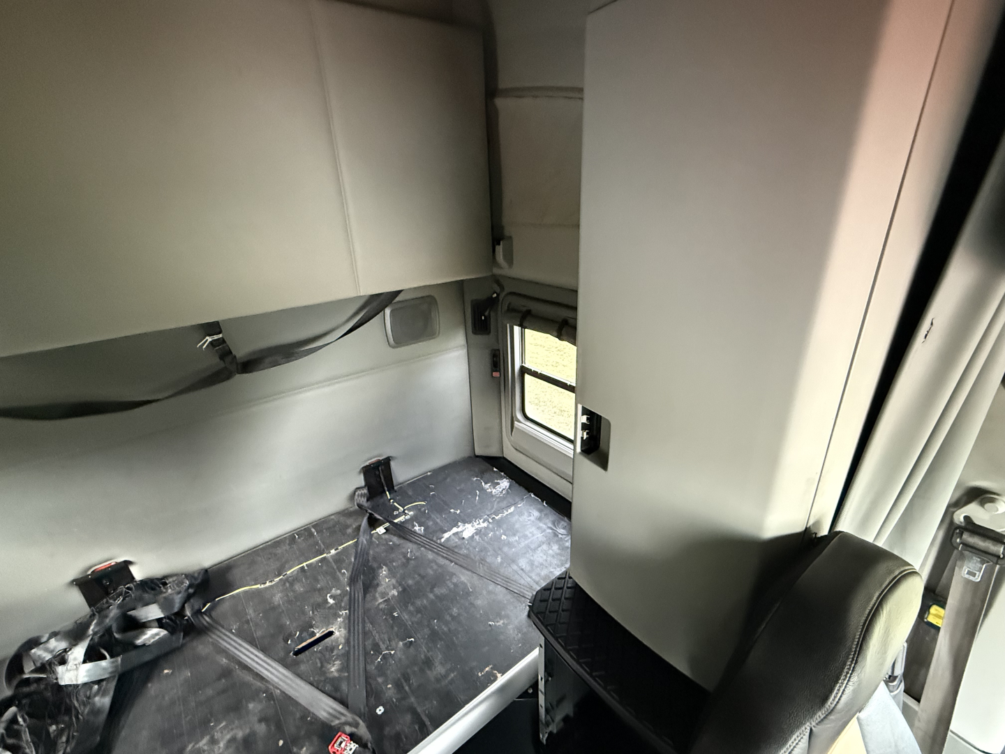 Kenworth T680 cab interior view with sleeper area and window.