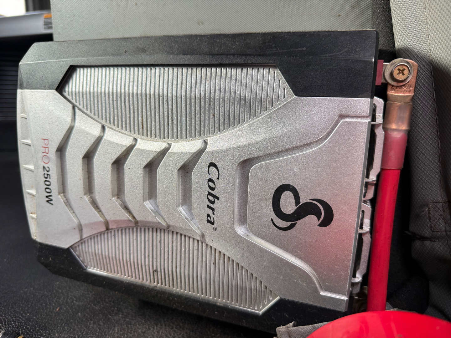 Kenworth T680 dashboard area showing a Cobra Pro2500W electrical/air unit with Cobra branding and a red battery/connector wire nearby.