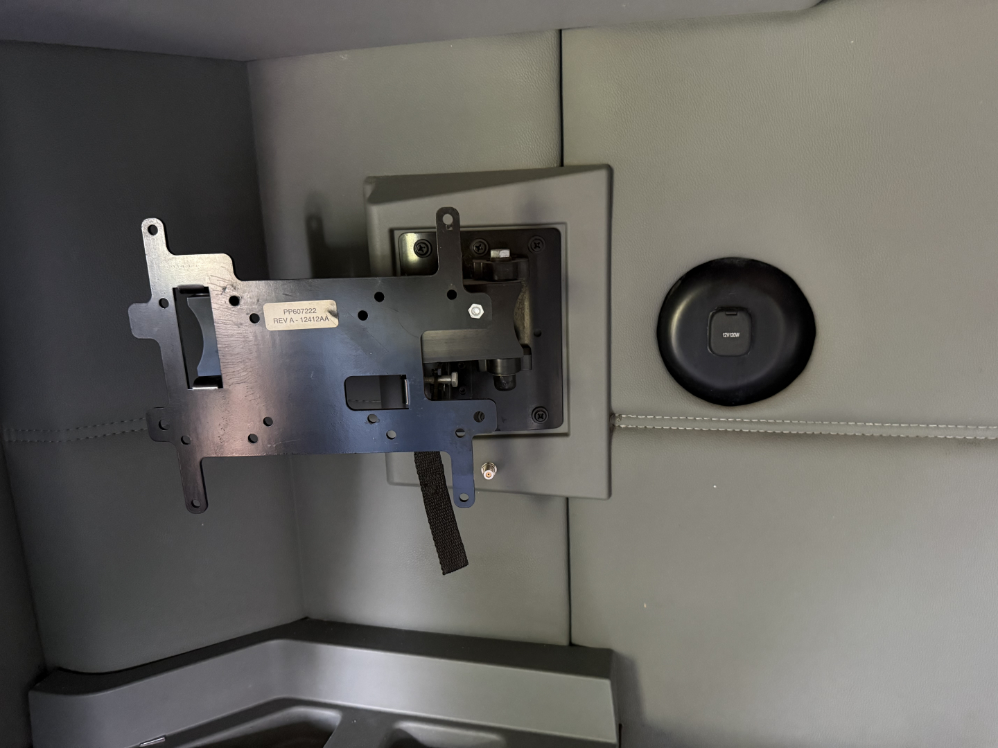 Kenworth T680 dash area showing a partially mounted instrument bracket and a circular power outlet on a gray interior panel.