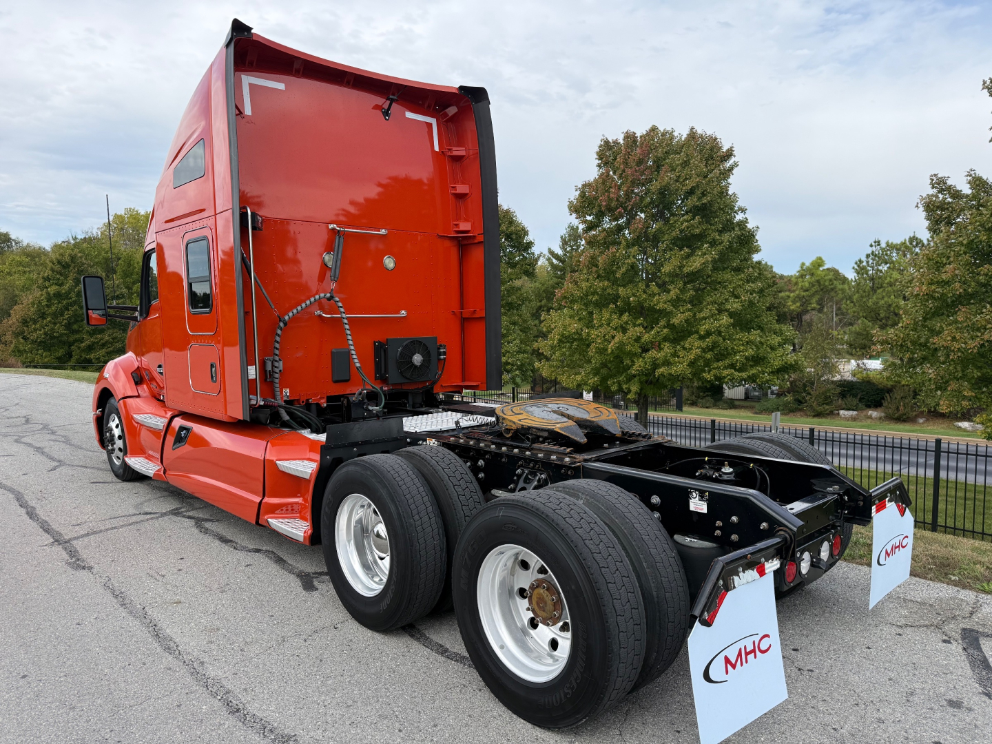 Kenworth T680 2021 tractor cab chassis view from rear-left showing red cab, dual rear axles, and empty fifth wheel rail.