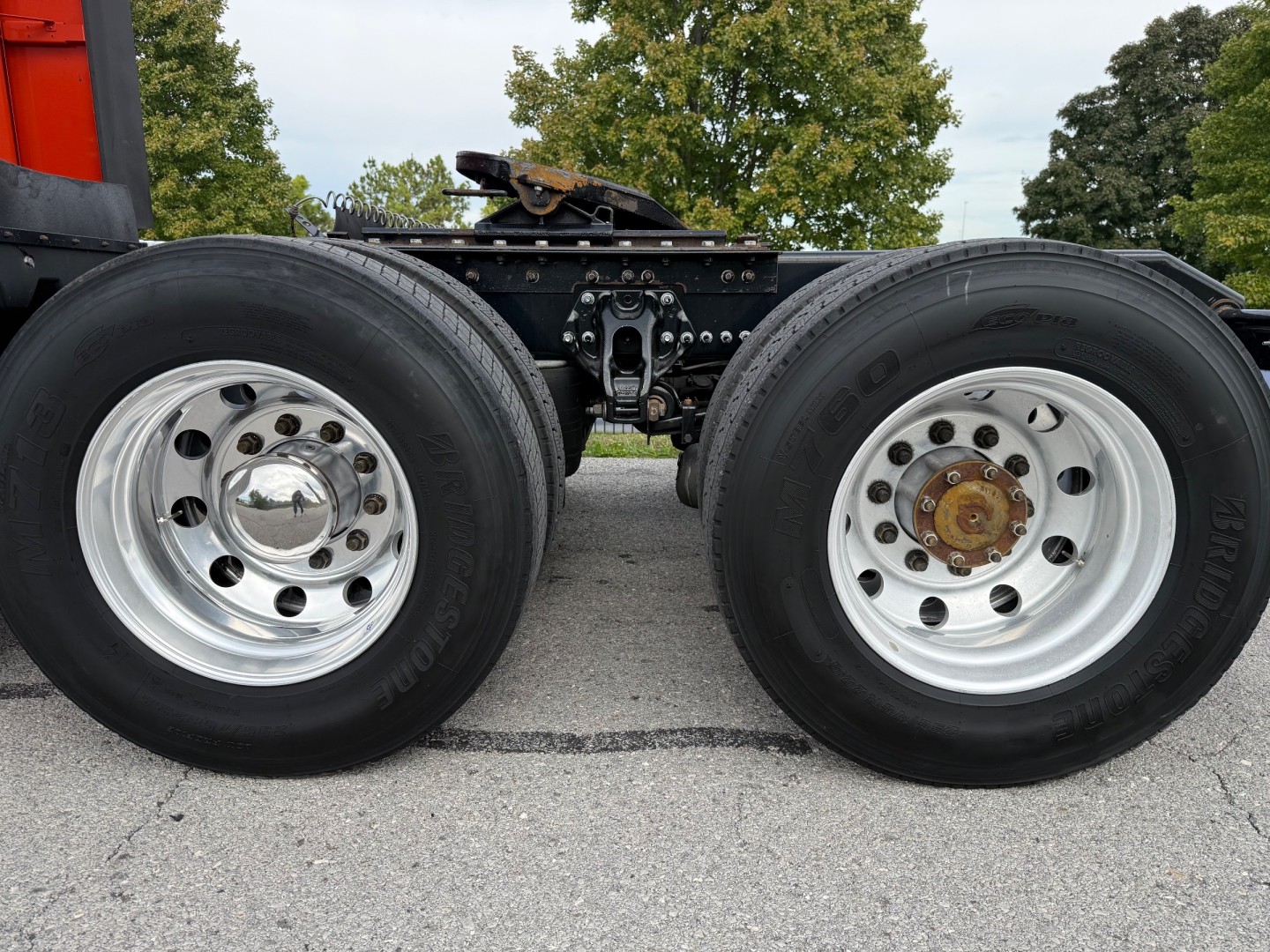 Kenworth T680 wheel area showing dual rear axles with polished chrome rims, tires, and brake components. No legible labels visible on tires.