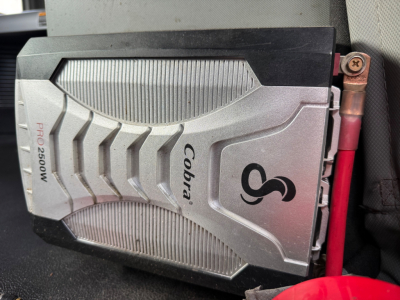 Kenworth T680 dashboard area showing a Cobra Pro2500W electrical/air unit with Cobra branding and a red battery/connector wire nearby.