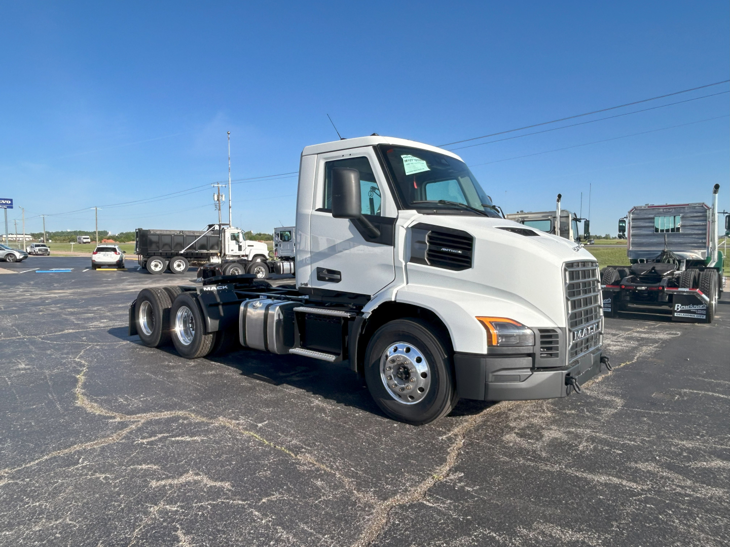 Truck cab and chassis side view of a new 2027 Mack AN64T conventional daycab with white exterior and chrome wheels.