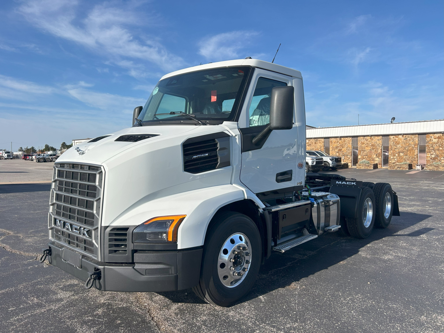 Mack AN64T conventional daycab truck in white, front-left angle showing cab, grille, and dual rear axles with chrome wheels.