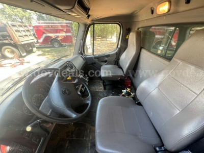 Cab interior of a 2017 Freightliner 114SD dump truck showing steering wheel, driver and passenger seats, dash area, and open floor with some exposed wiring.