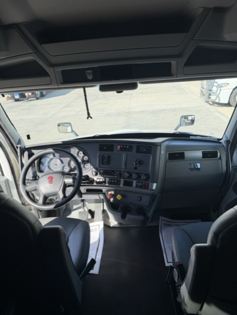 Cab interior of a Kenworth T680 truck showing dashboard with steering wheel, gauges, and overhead panels.