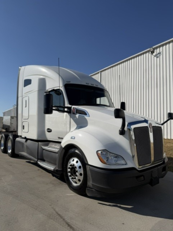 Kenworth T680 tractor-trailer in-service showing aerodynamic white cab and sleeper, front grille, and side mirrors.