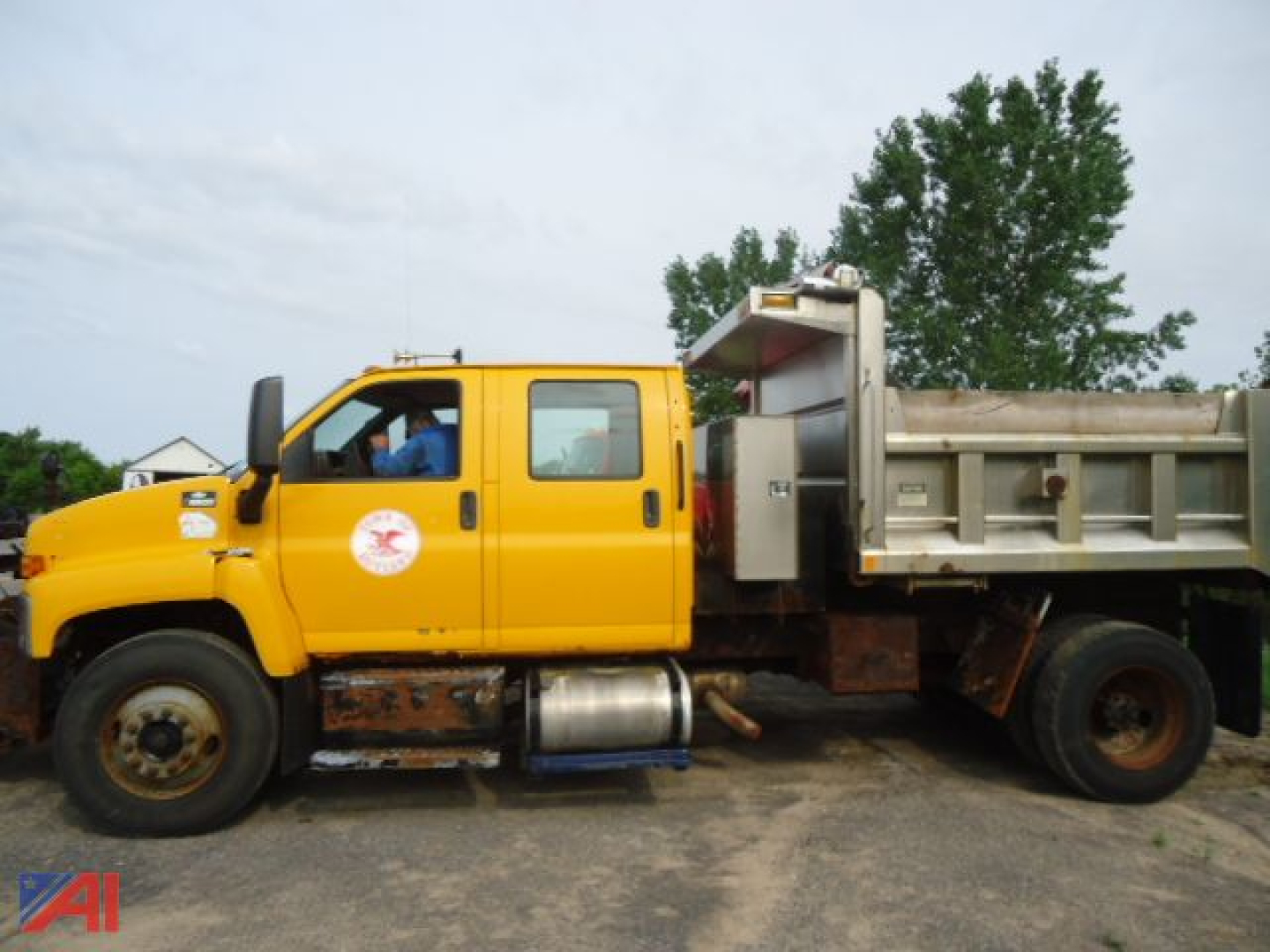 Yellow 2007 Chevrolet Kodiak C8500 dump truck with plow showing side view and dump bed in background.