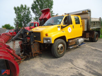 Yellow 2007 Chevrolet Kodiak C8500 dump truck with plow and dump bed, view of front-left side showing plow at front, large side mirrors, diesel fuel tanks, and utility equipment.