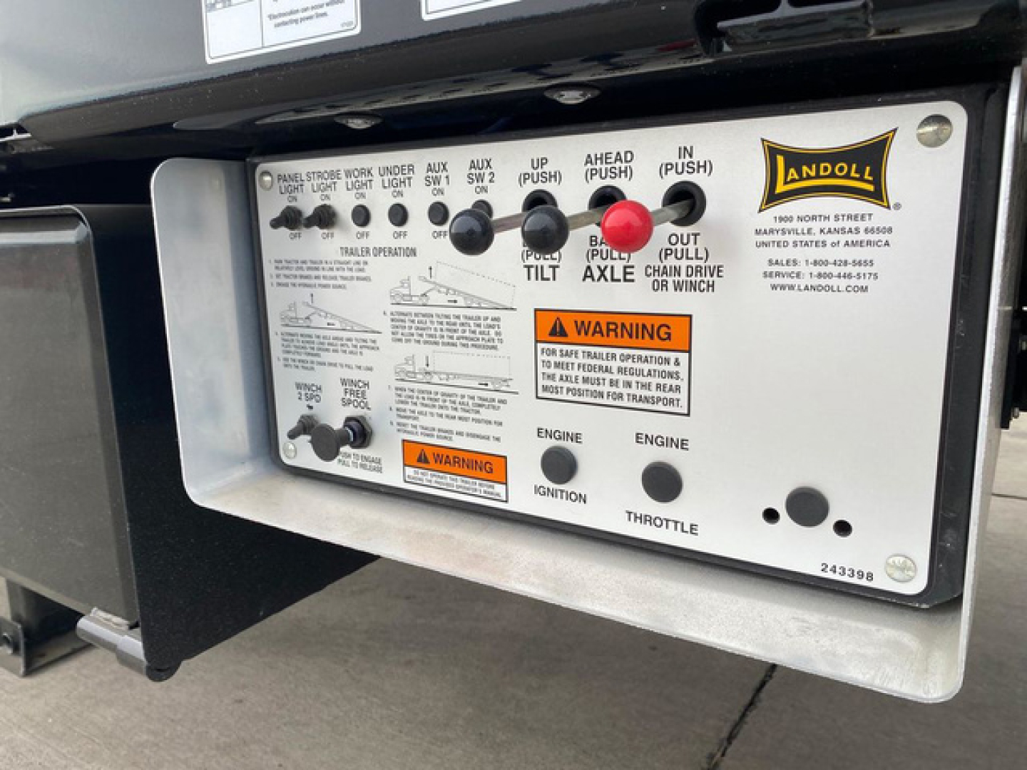 Container trailer control panel with switches and labels showing various functions and warnings, Landoll badge on right side.