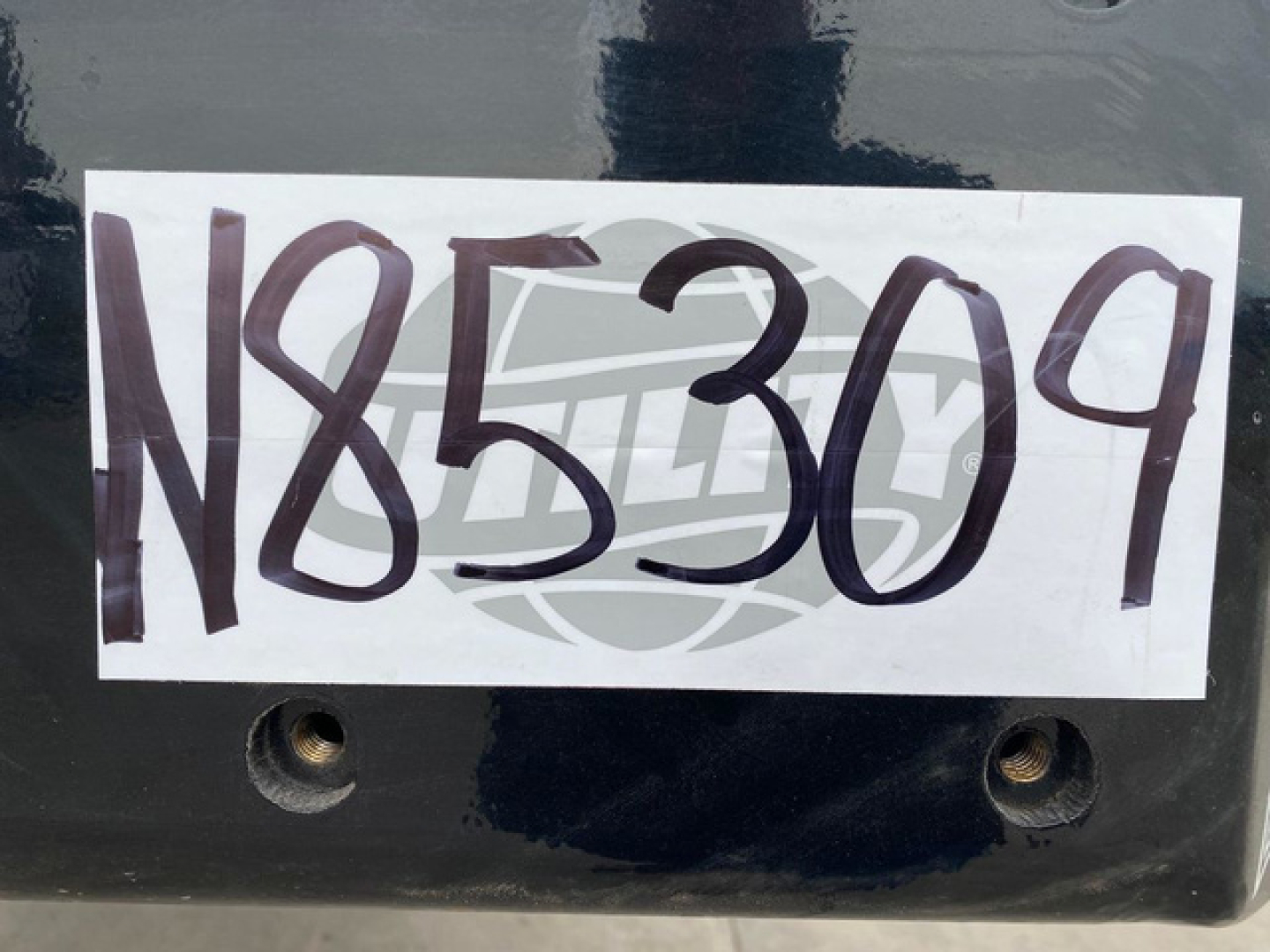 Large white label with handwritten stock number N85309 on a dark surface of a Landoll container trailer.