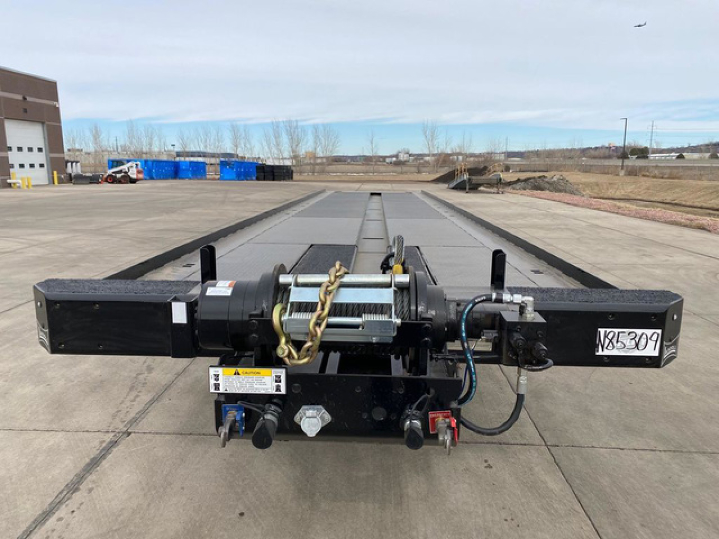 Container trailer hitch assembly with hydraulic winch and control cables showing central beam and mounting hardware.