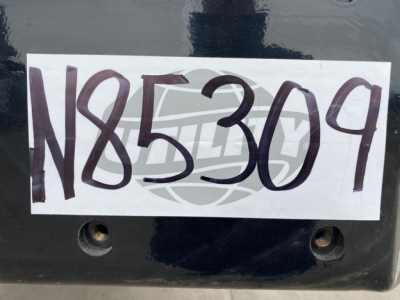 Large white label with handwritten stock number N85309 on a dark surface of a Landoll container trailer.