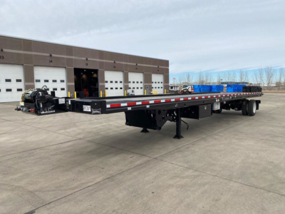Flatbed trailer with long tandem axles and gooseneck hitch in front, Landoll container trailer model, no visible branding text legible on the equipment.