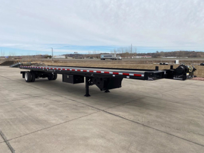 Flatbed trailer for container transport showing long black frame, tandem axles, landing gear, and gooseneck hitch.