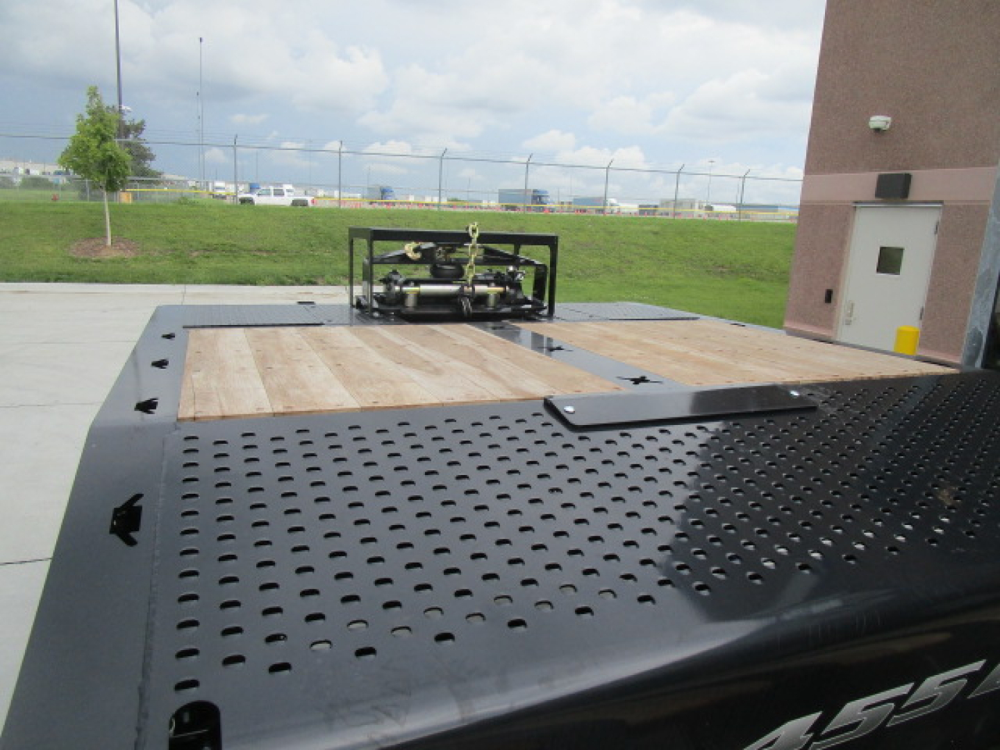 Perimeter view of a new Landoll 455 trailer flatbed with a perforated steel surface and wooden deck sections, stock N86226.
