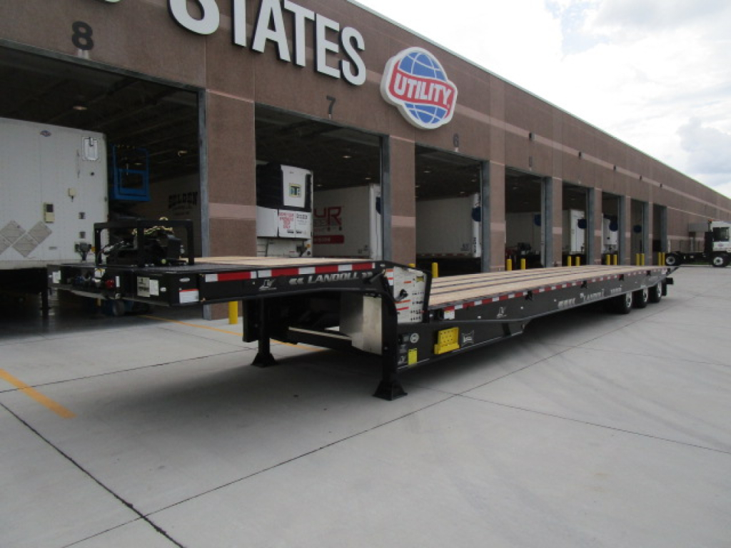 Trailer showing a Landoll 455 traveling axle trailer in front of a service bay facility.
