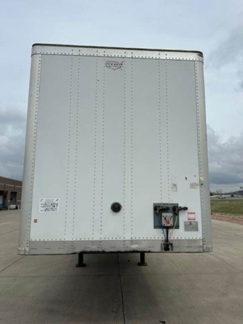 Rear view of a white 2017 Wabash van trailer showing rear doors, bumper, hitch, and leveling legs with VIN sticker and data labels visible.