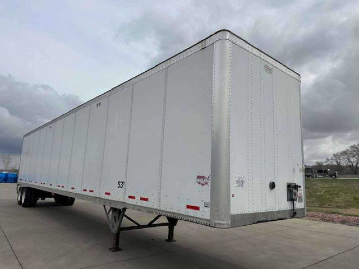 Trailer side view showing a white Wabash van trailer with side panels, 53' length marking, landing gear, and rear doors.