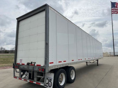 Trailer side view of a 2017 Wabash van trailer showing tandem wheels and rear lights.