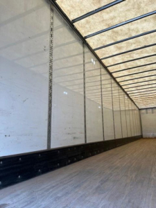 Interior of a Wabash trailer with side panels and ribbed ceiling, empty cargo area showing white walls and black lower edge trim.