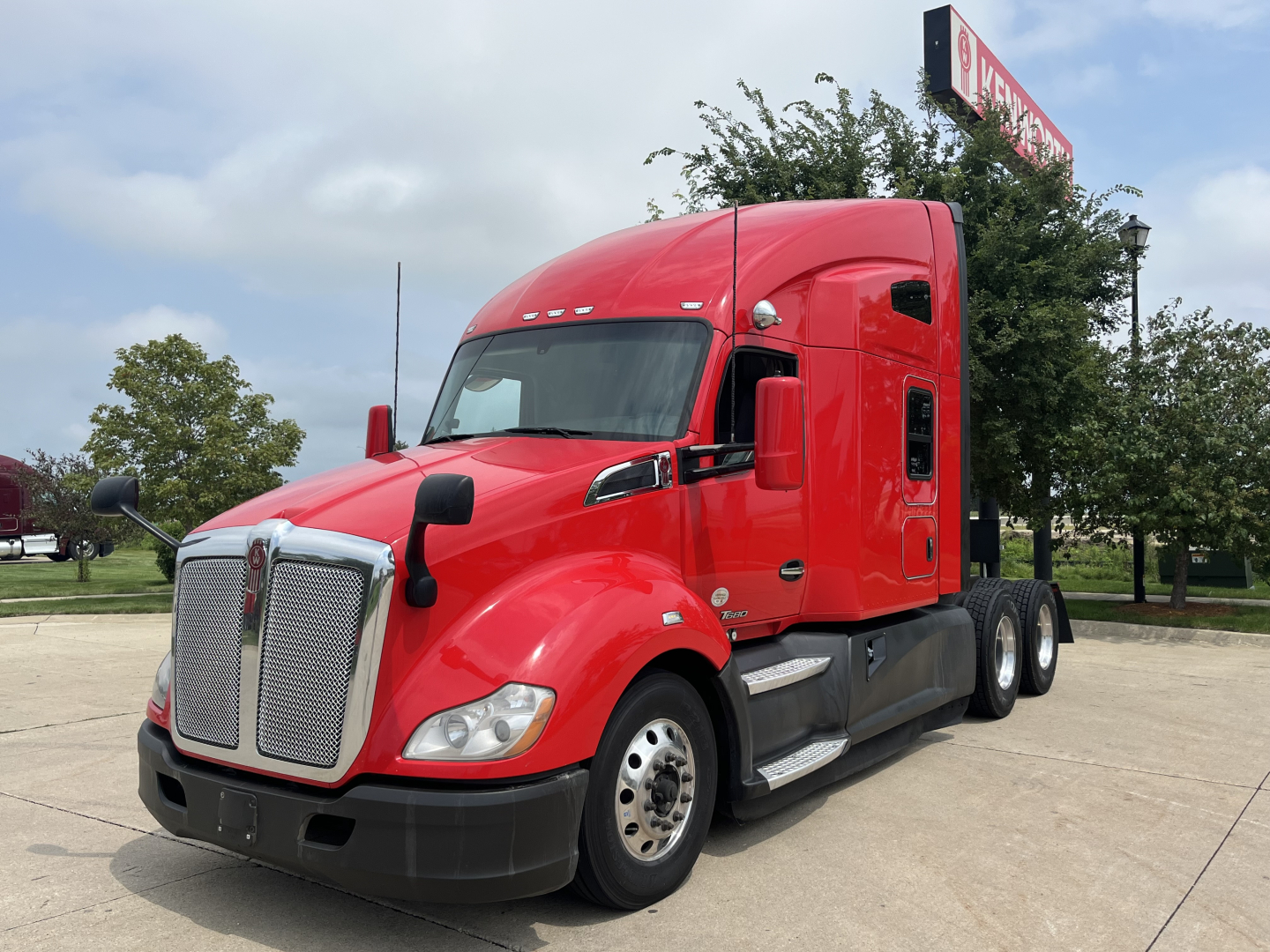 Kenworth T680 heavy-duty truck in red, front three-quarter view showing grille, headlights, and side mirrors.