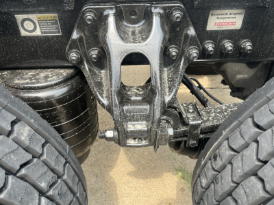 Kenworth T680 rear suspension and fifth wheel area showing heavy-duty hitch assembly and dual tires.