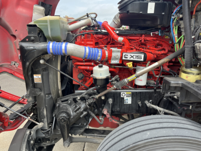 Kenworth T680 engine bay showing X15 badge on engine cover and red engine block with blue silicone intercooler hose.
