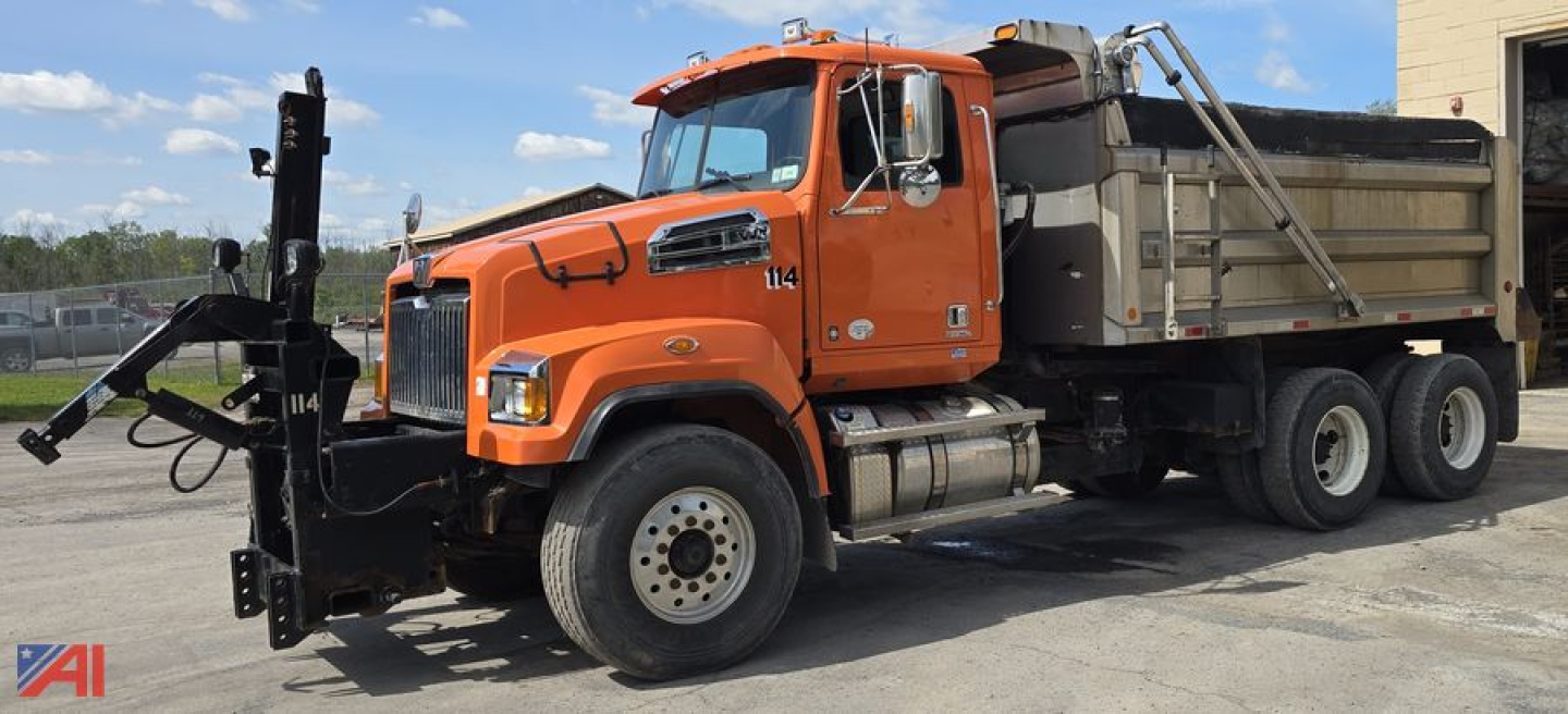 Dump truck with orange cab and dump bed, side view showing front hitch and hydraulic apparatus
