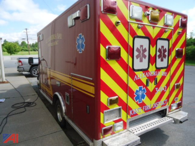Ambulance side and rear showing red body with yellow diagonal stripes and Star of Life symbols, rear doors with medical decals, emergency lights, and reflective chevrons.