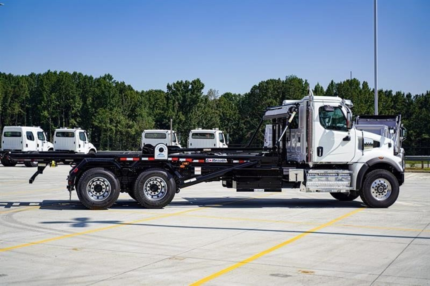 Side view of a new Western Star 47X rolloff truck on a paved lot showing cab, chassis, and wheel configuration.