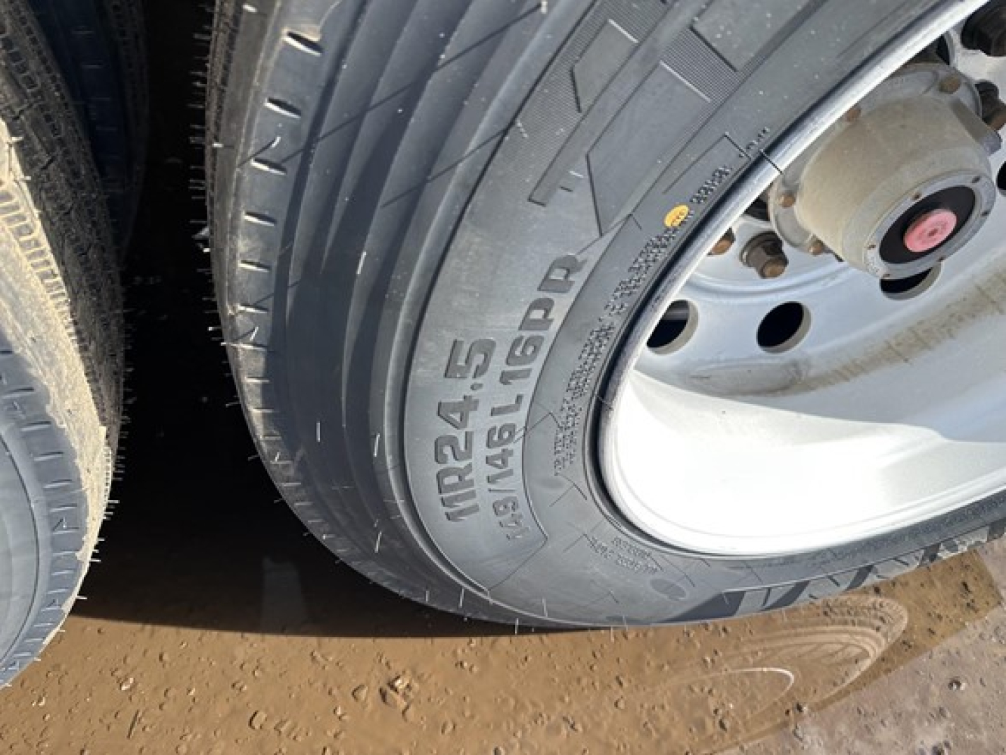 Trailer wheel and tire close-up showing Michelin X或 tread pattern and tire size marking NRS24-5 or similar on sidewall; aluminum end dump trailer wheel well.