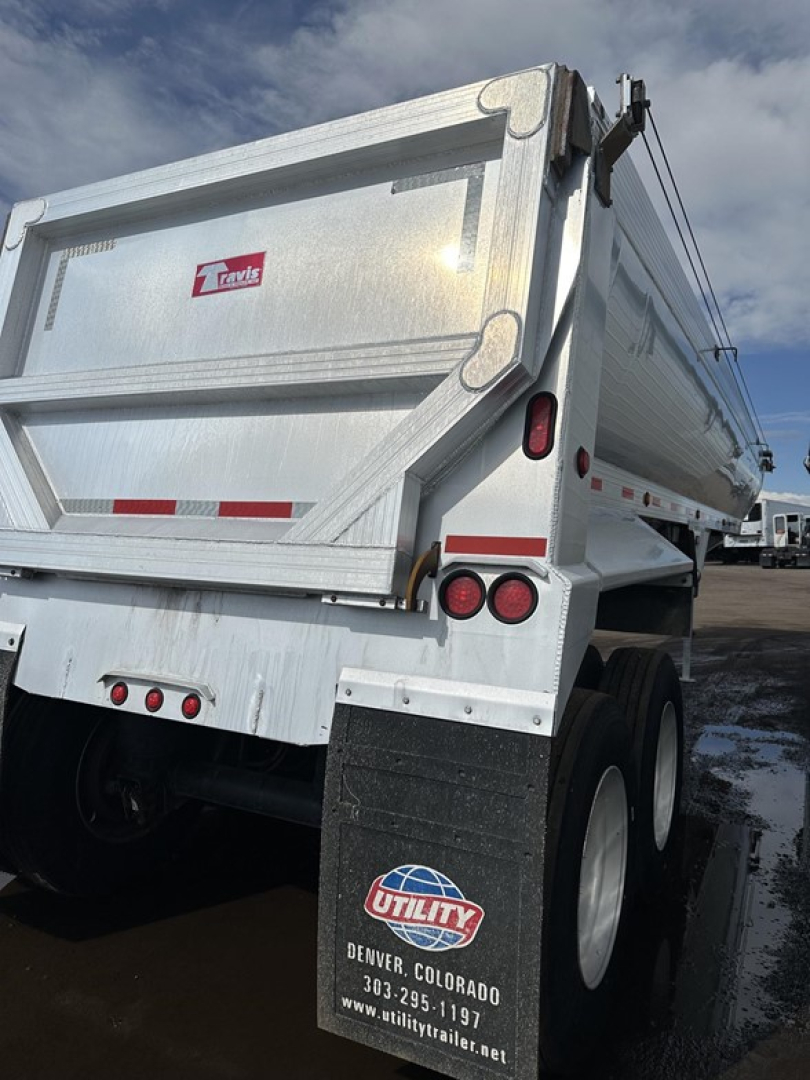 Travis frameless aluminum end dump trailer rear view showing dual wheels, tail lights, and stamped aluminum bed.