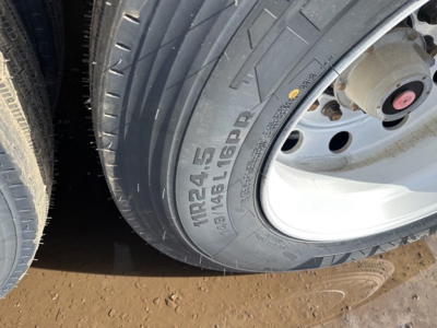 Trailer wheel and tire close-up showing Michelin X或 tread pattern and tire size marking NRS24-5 or similar on sidewall; aluminum end dump trailer wheel well.
